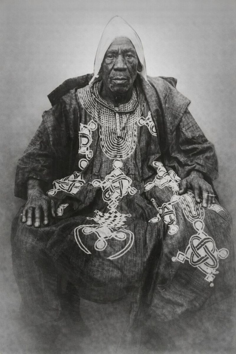 Photograph of Ogboni Fapohunda, seated in an embroidered agbada and white cap