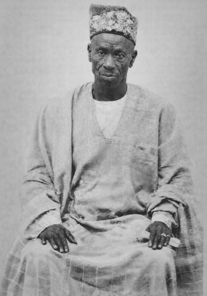 Photograph of Pa David Seriki Tomori Fapohunda, seated in a light agbada and embroidered cap